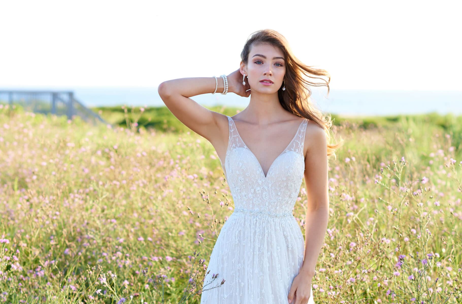 Brunette model in field of flowers wearing Martin Thornburg wedding dress