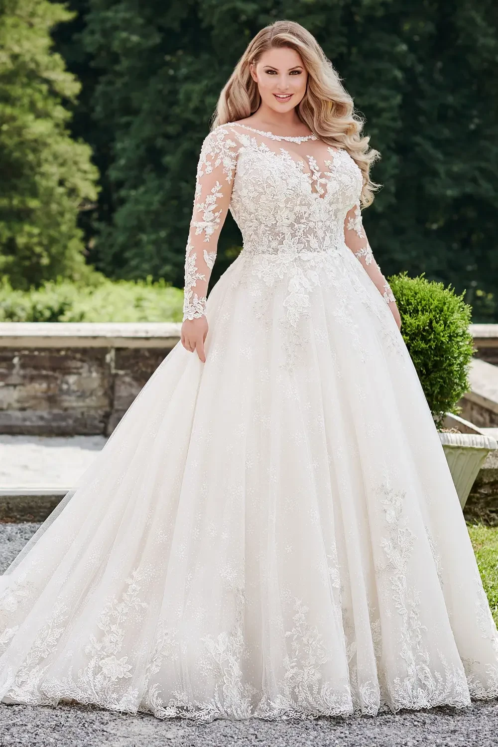 A woman in a beautiful, elegant wedding dress with long sleeves, featuring intricate lace details and a full skirt.