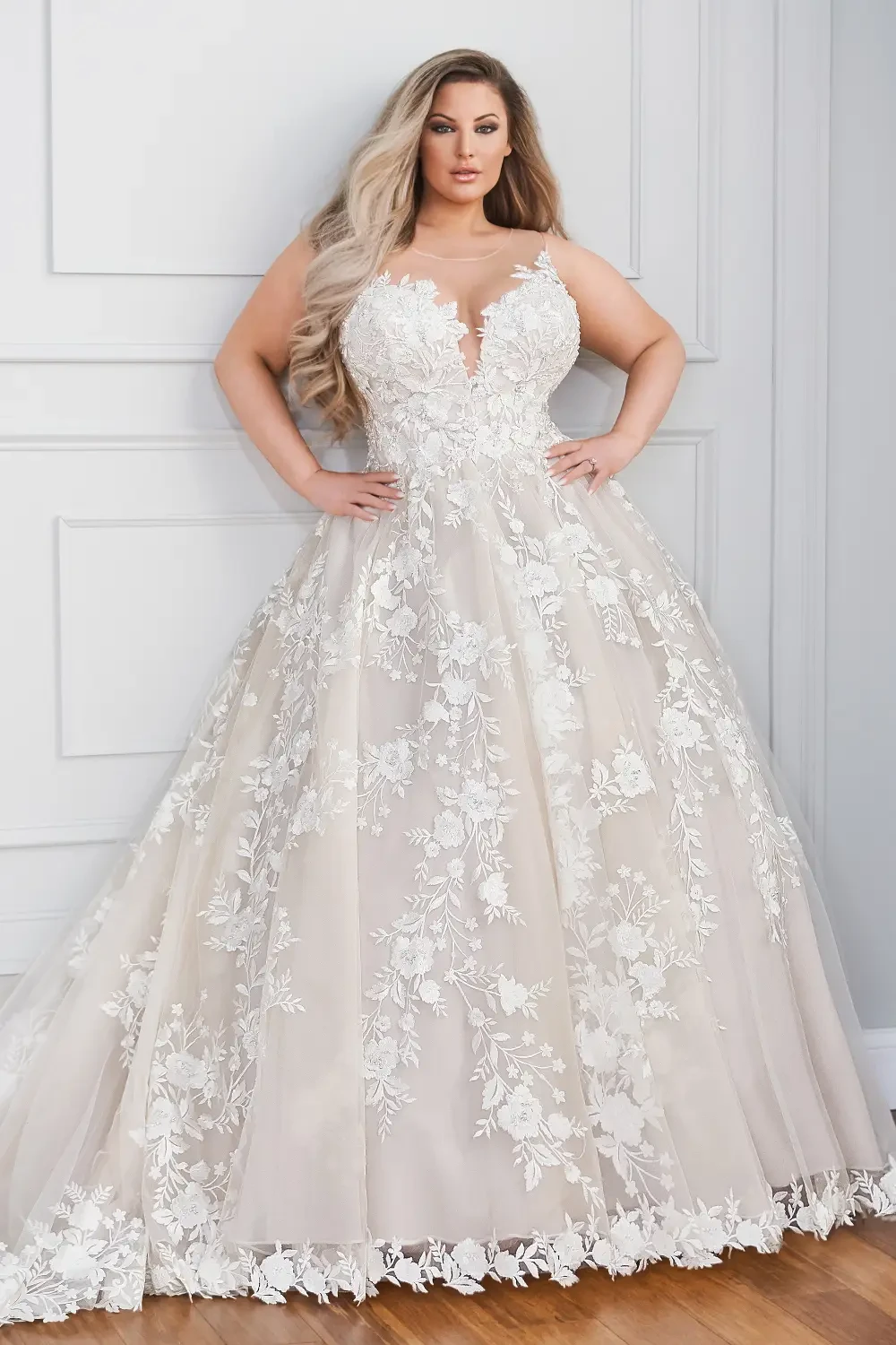 A woman wearing a beautiful, embellished wedding dress with a deep V-neckline and floral appliqu&eacute;s.