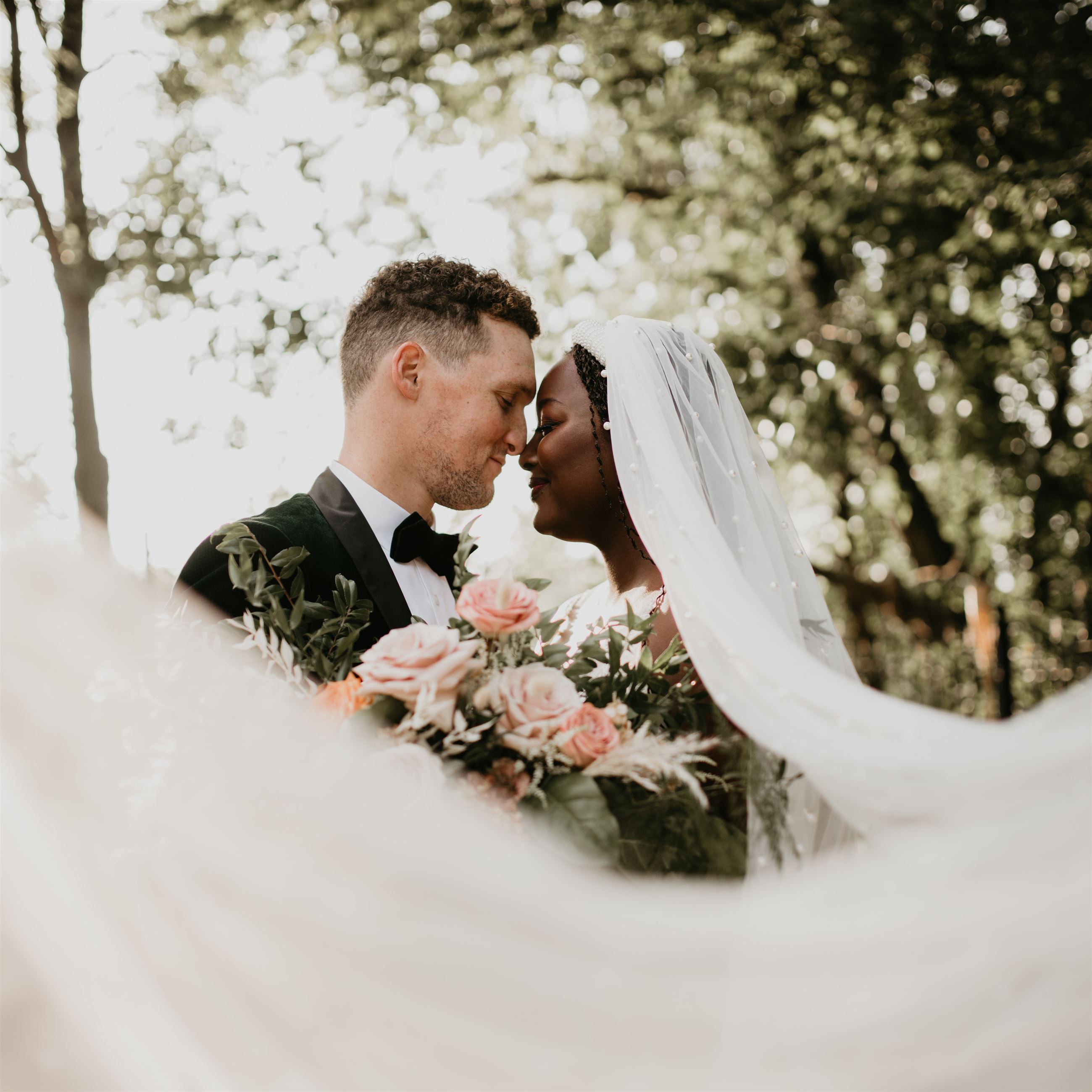Bride and groom holding each other with bride's veil blowing in wind