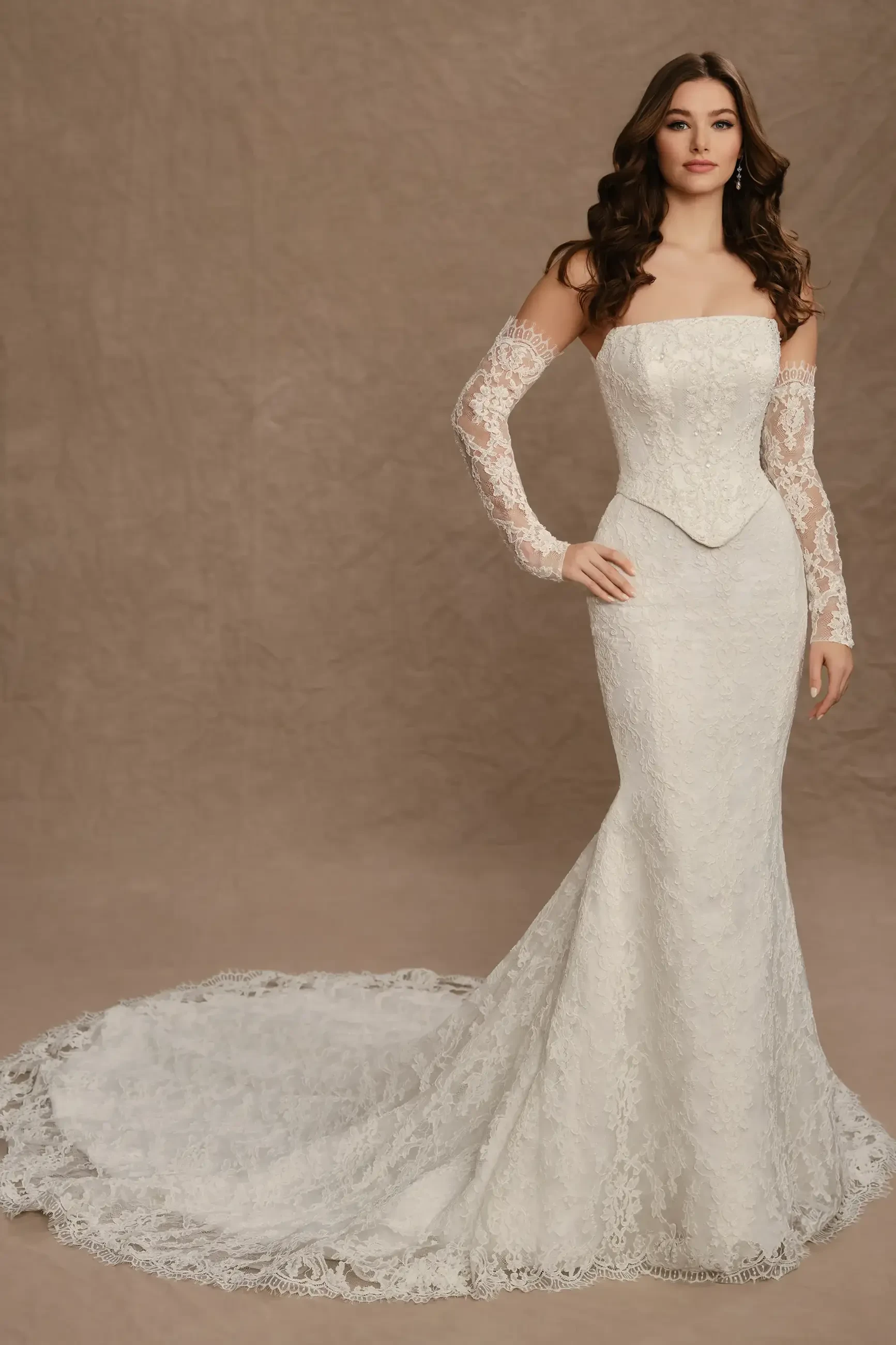 A model wearing an elegant white wedding dress with long lace sleeves and a mermaid silhouette, featuring a train.