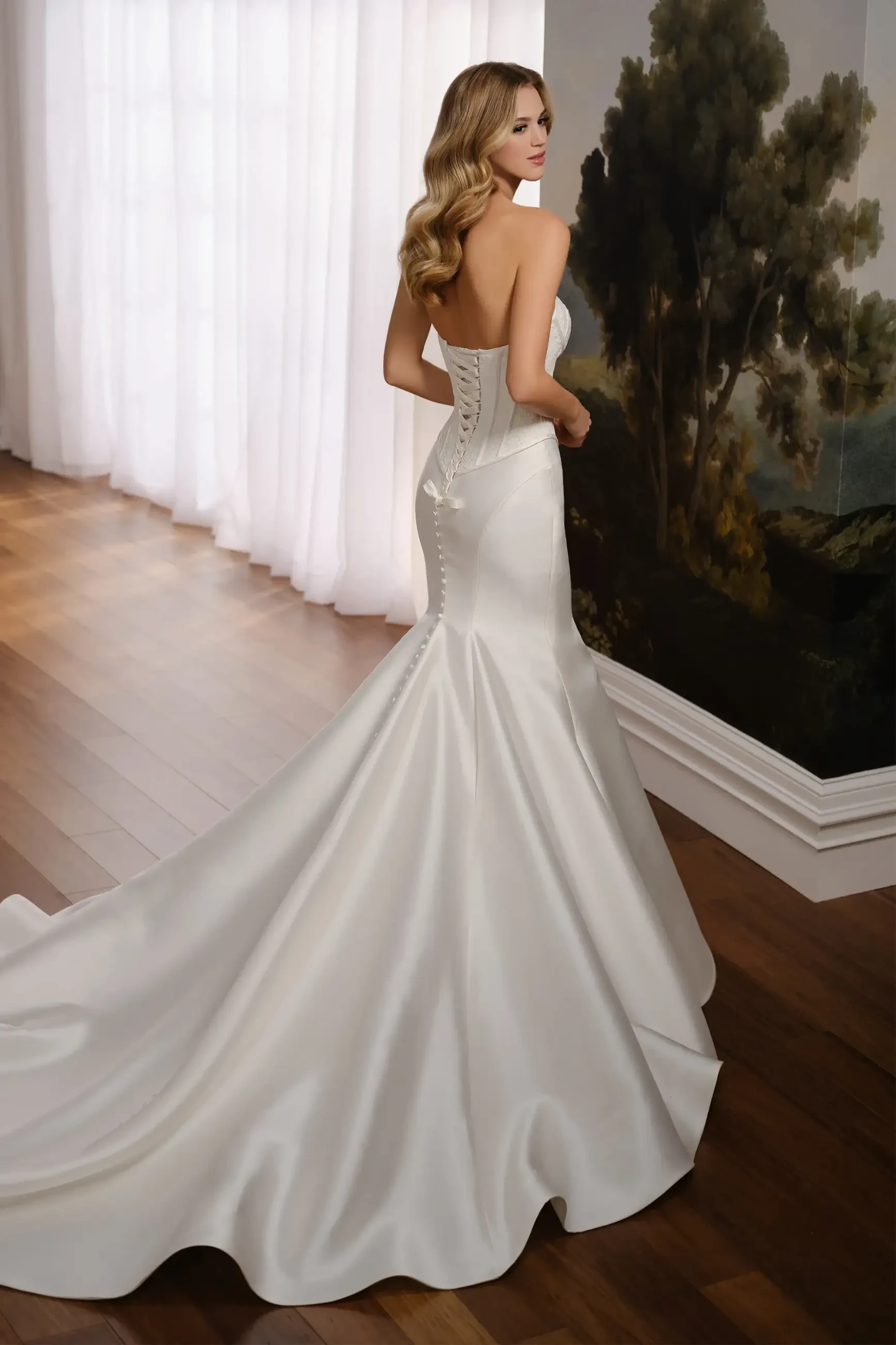 Model is wearing a trumpet gown with an allover lace bodice, sleek Mikado skirt, and back modesty panel.
