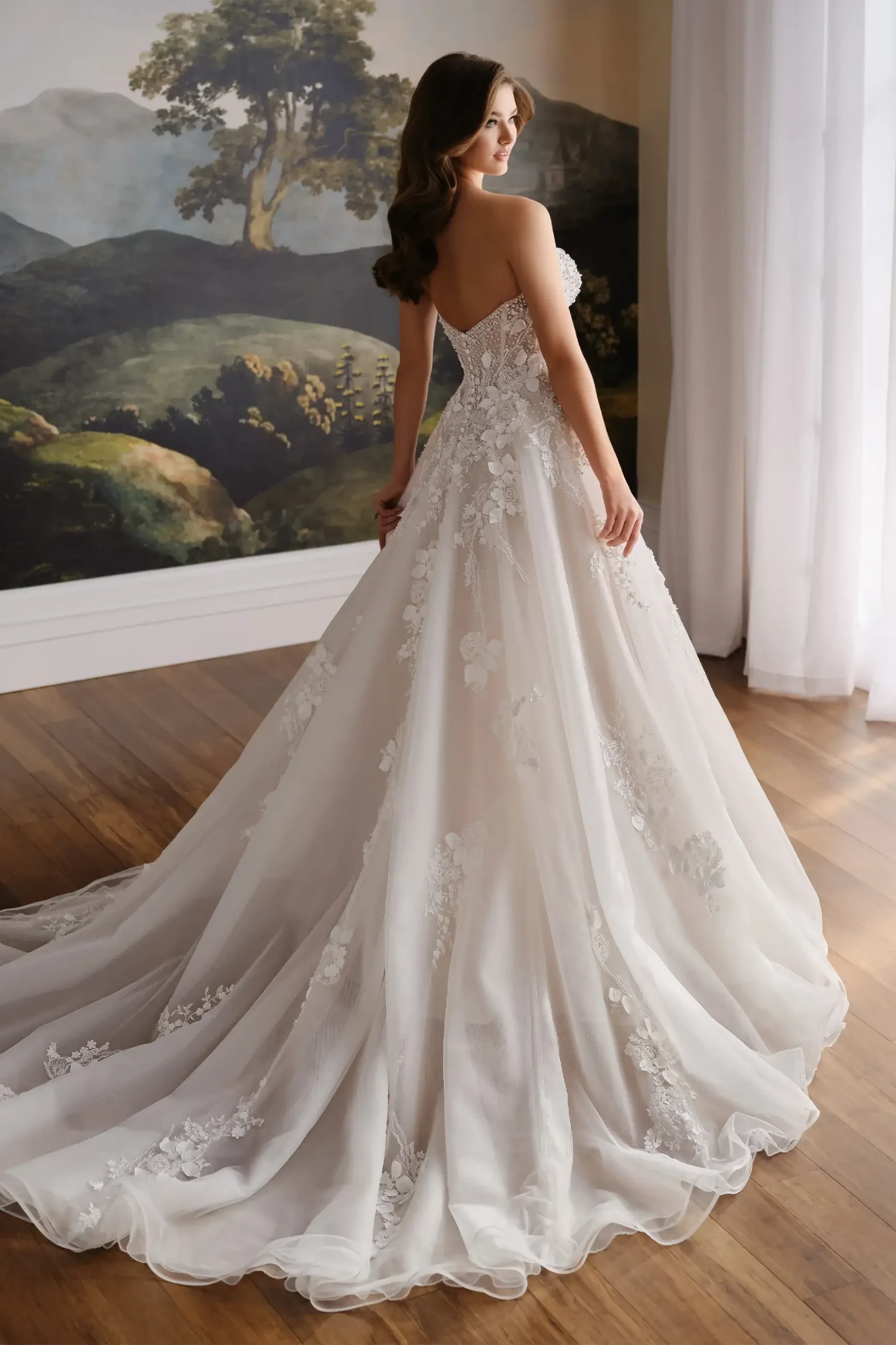 Model is wearing a strapless organza ball gown with a sweetheart neckline and removable pearl-beaded straps.