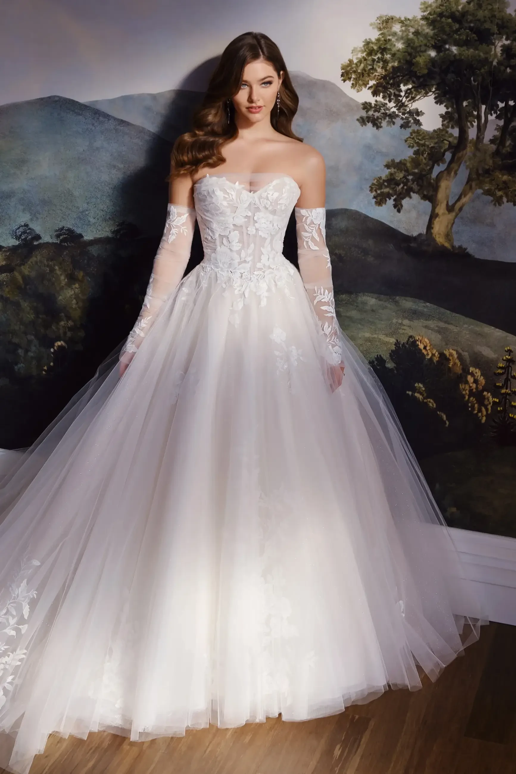 Model is wearing the Hadley ball gown (MT8108), showcasing a soft shimmer lace and tulle design with a sweetheart neckline, glitter illusion bodice, and matching gauntlet sleeves.