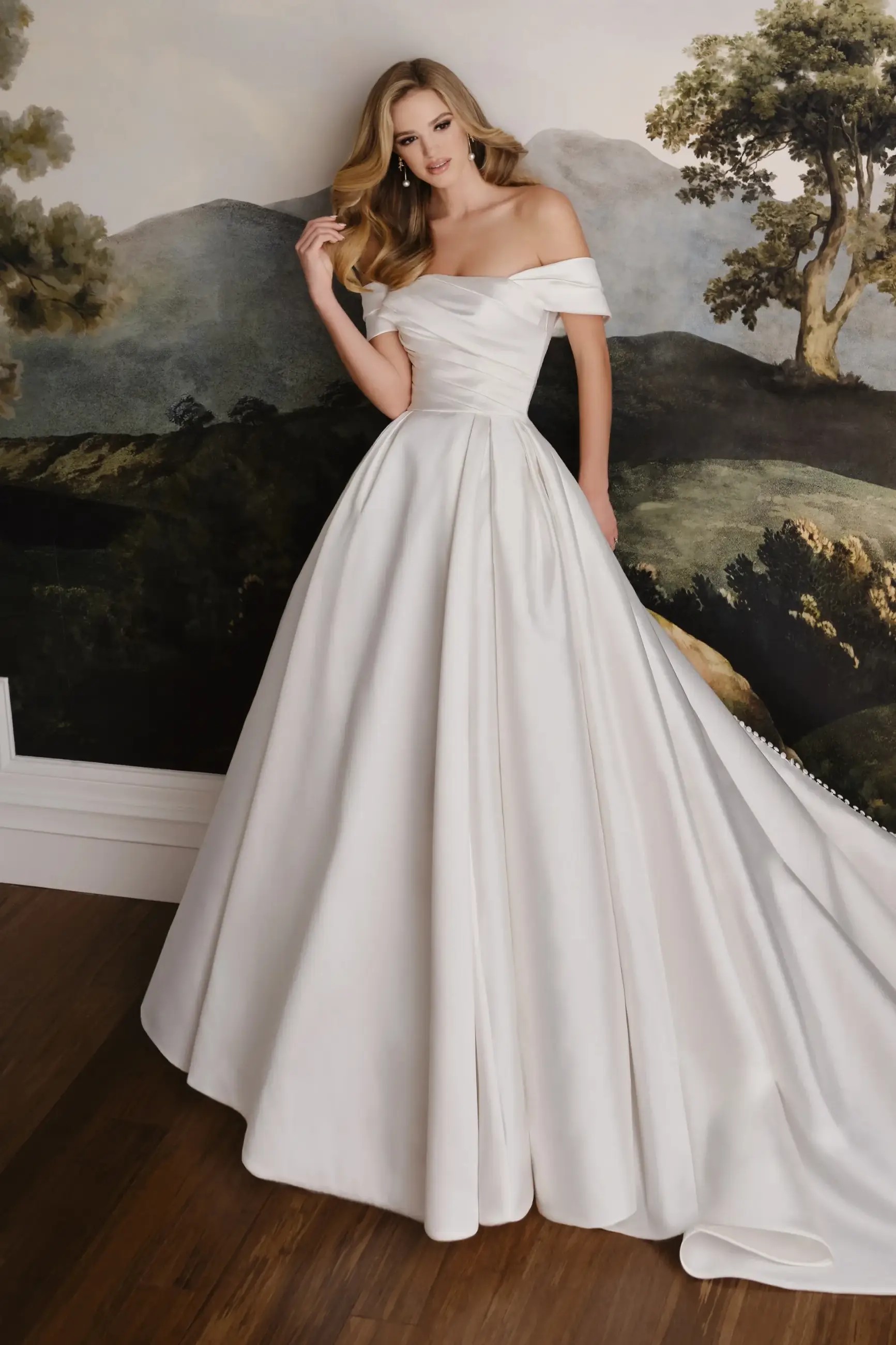 Model is wearing a mikado and organza bridal gown with a sculpted neckline