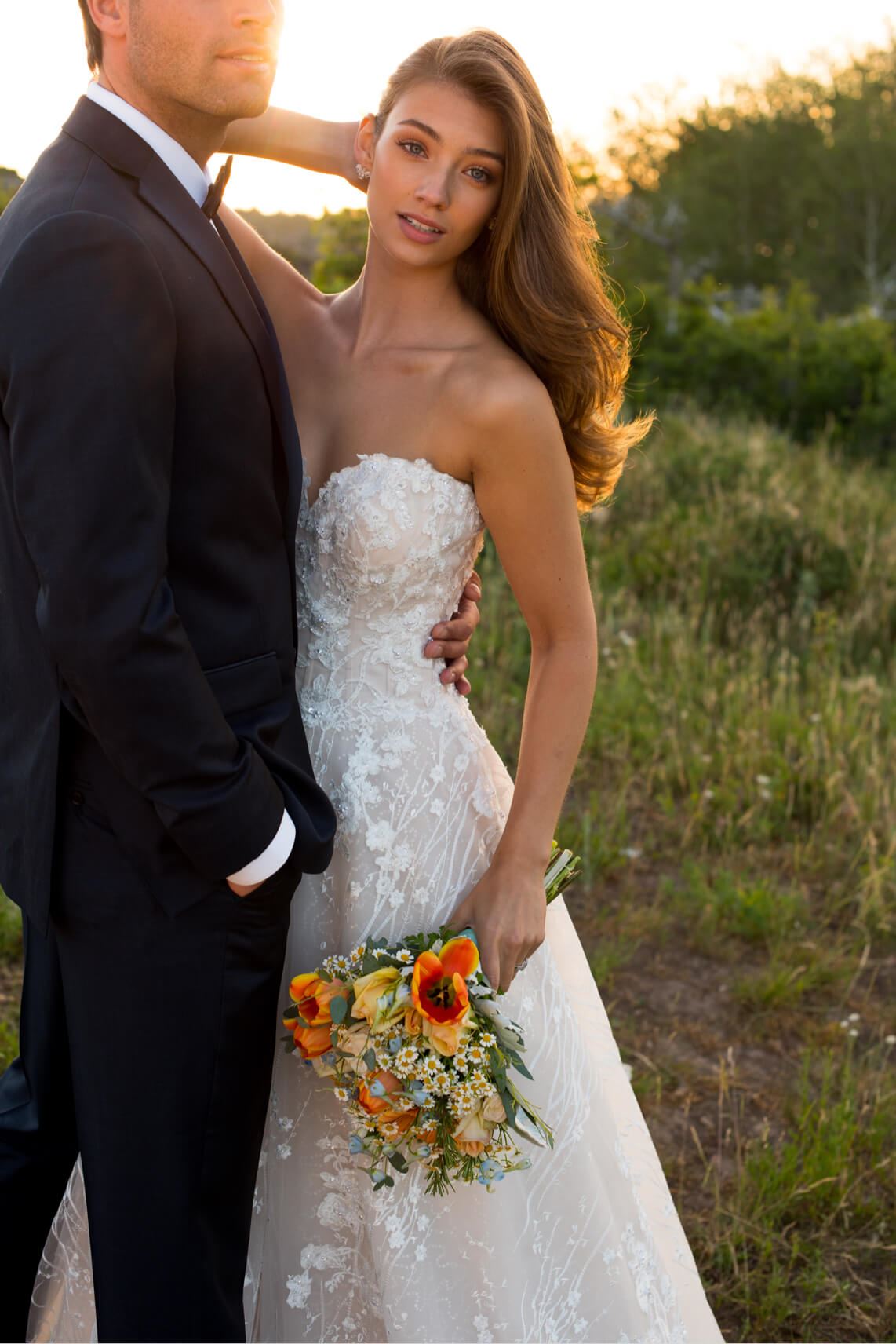 Brunette bride in Martin Thornburg wedding dress and groom in field