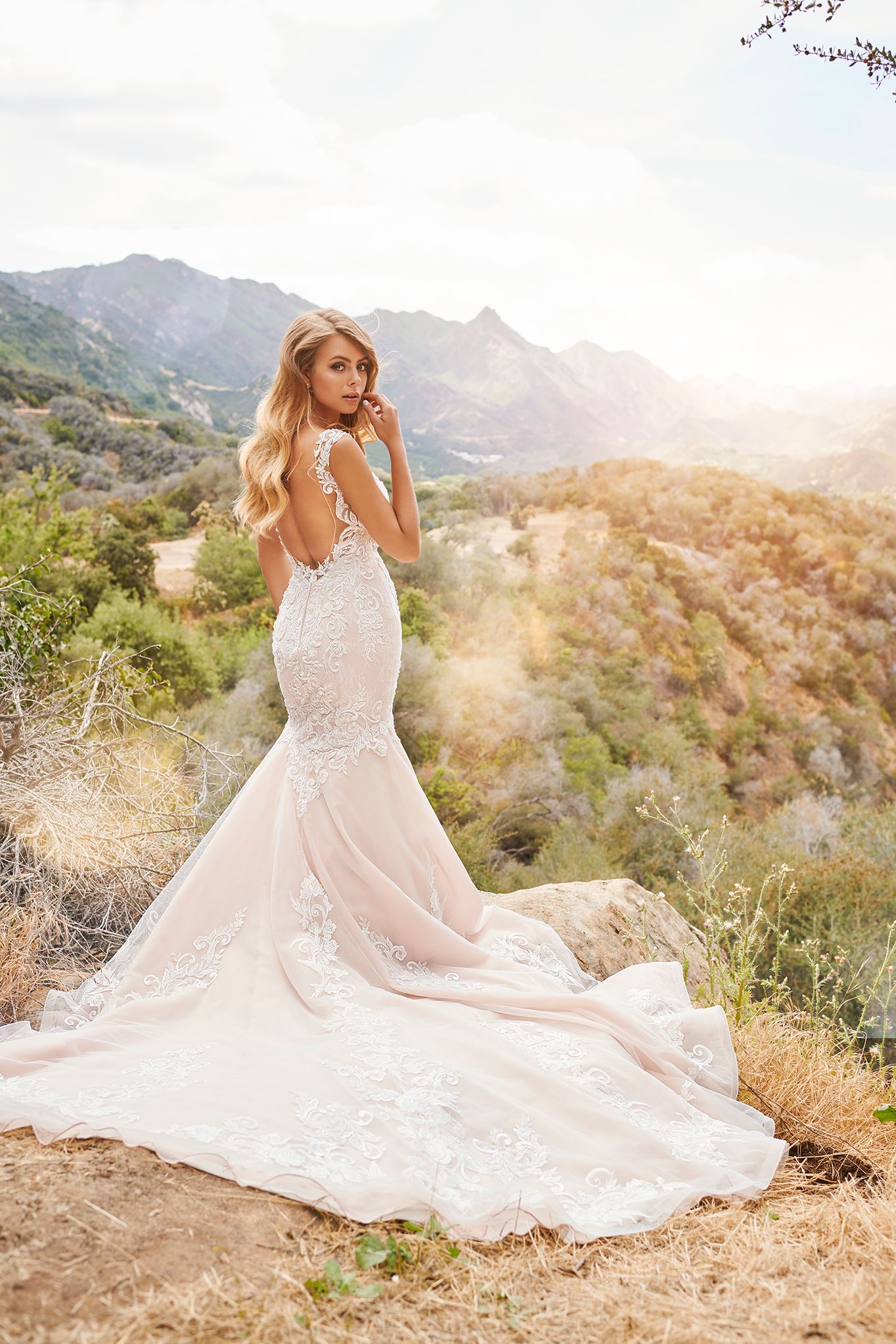 Blonde bride in open back wedding dress in field