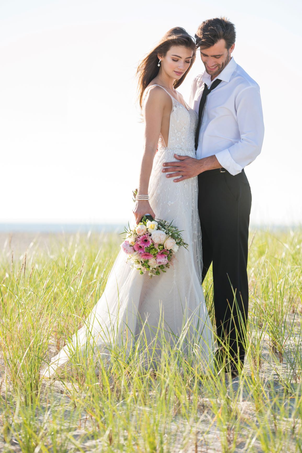 Brunette bride wearing Martin Thornburg wedding dress standing with groom