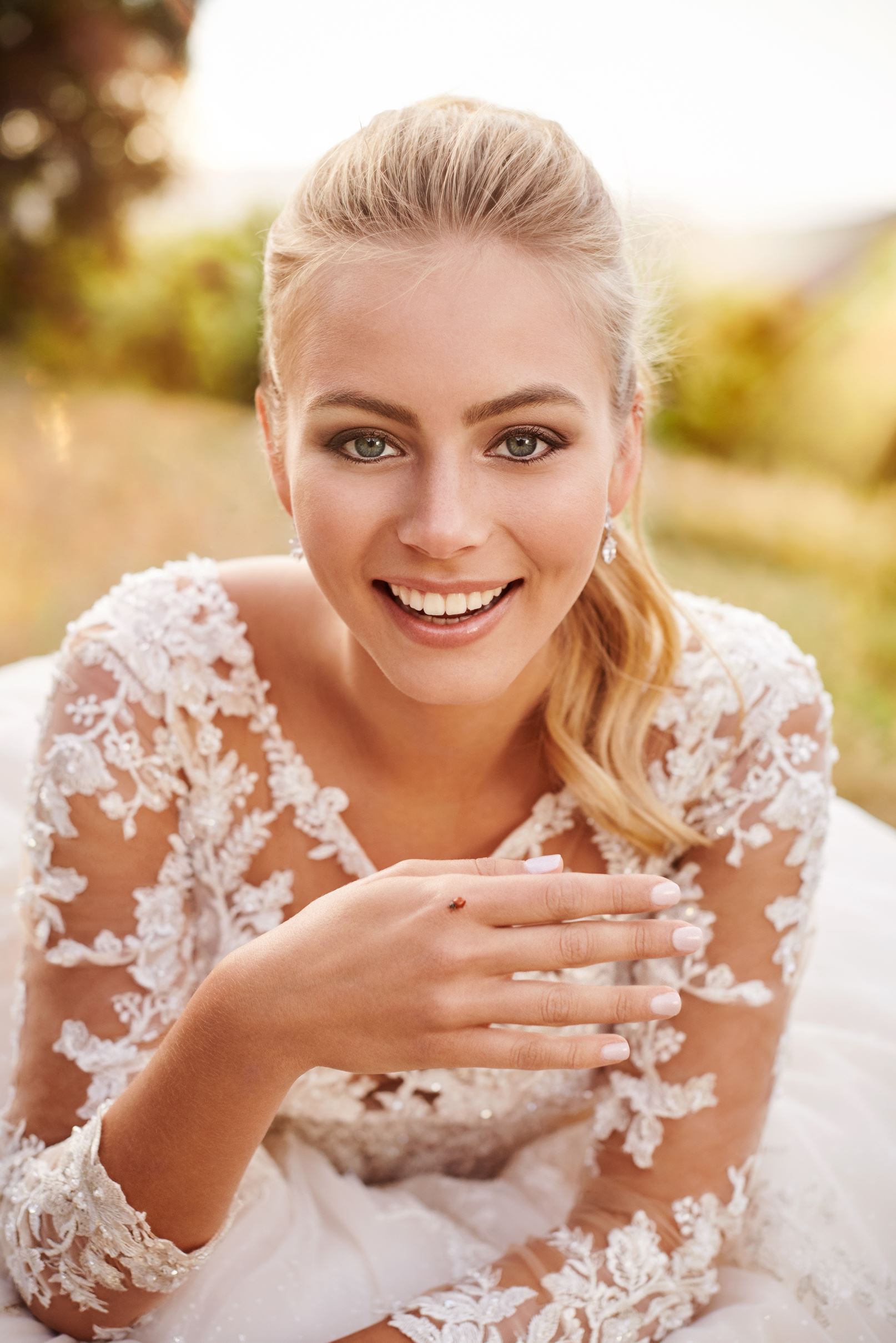 Blonde bride in long sleeve wedding dress holding ladybug