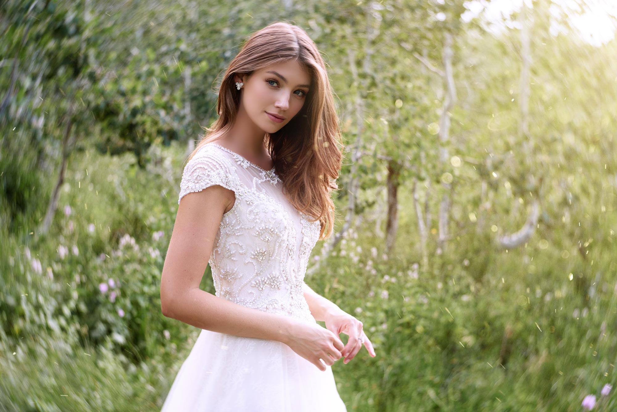 Brunette bride in field wearing short sleeve wedding dress