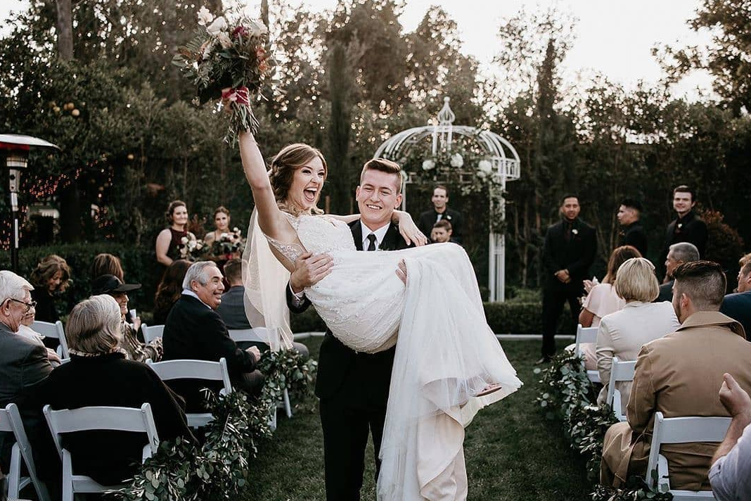 Groom carrying bride down the aisle after getting married