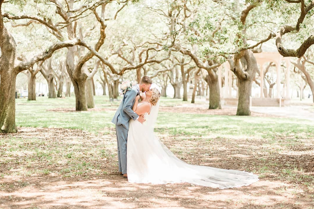 bride and groom kissing in field