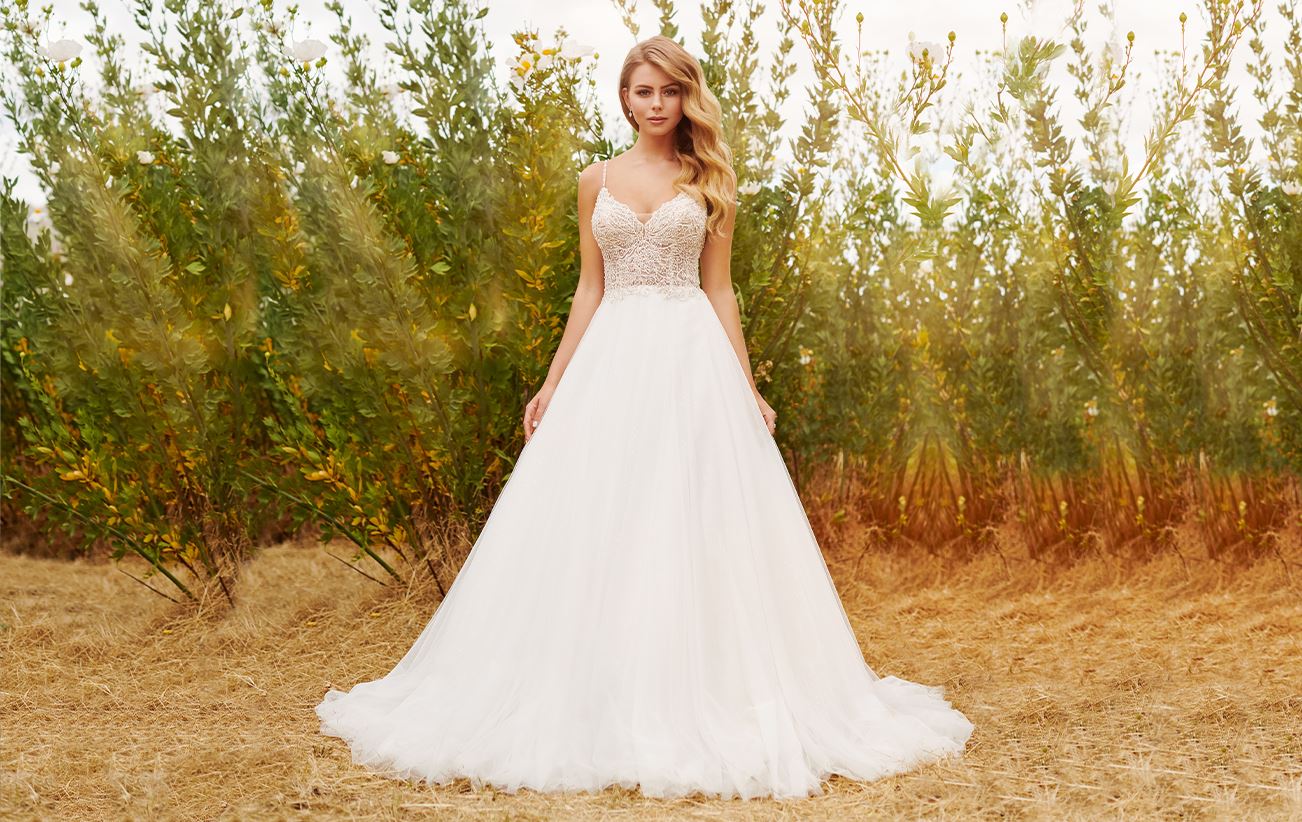 Blonde model in field wearing white wedding dress
